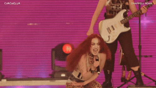 a woman with red hair singing into a microphone with the words coachella on the bottom