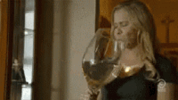 a woman is holding a large glass of wine in her hand .