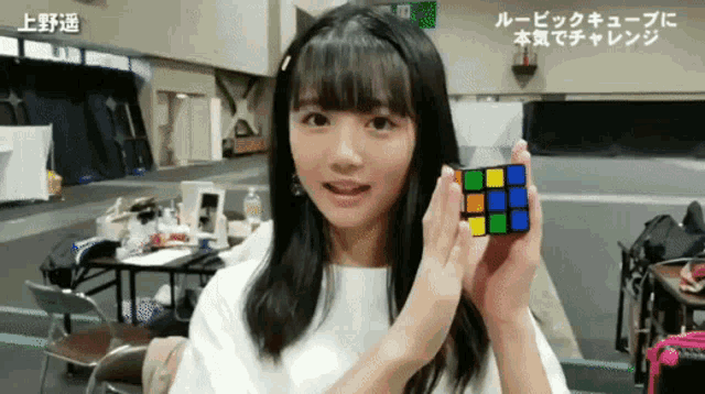 a girl is holding a rubik 's cube in her hand