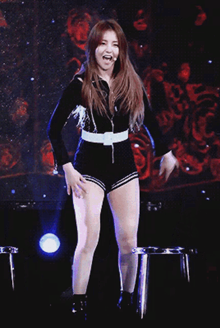 a woman in shorts and a black jacket is dancing on stage