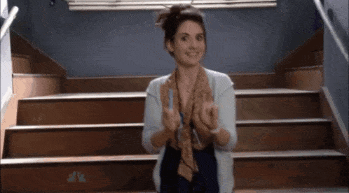 a woman is standing in front of a set of stairs giving the middle finger .