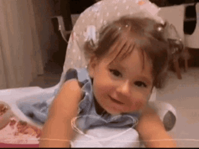 a little girl is sitting in a high chair smiling .