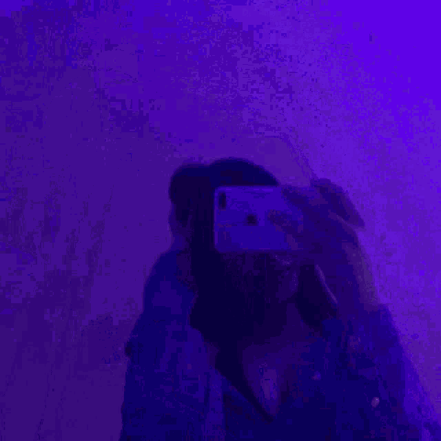 a woman is taking a picture of herself in a mirror with a cell phone .