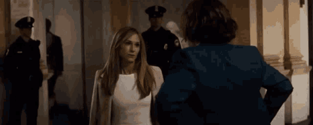 a woman in a white dress is talking to another woman in a blue suit .