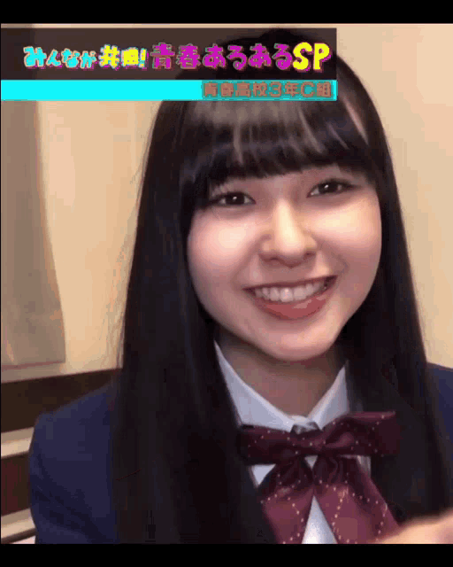 a girl in a school uniform is smiling in front of a screen that says sp