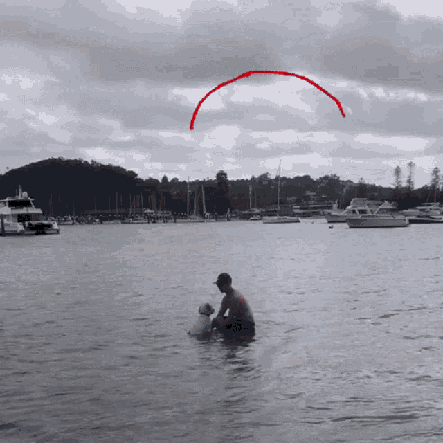 a man sits in the water with his dog