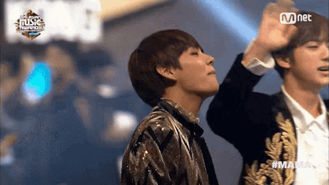 a couple of men standing on a stage with mnet written on the bottom