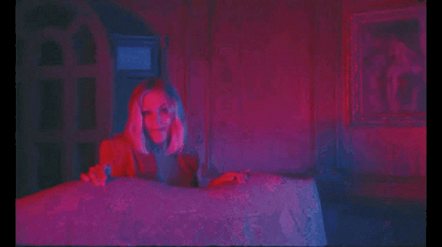 a woman in a bra and jacket is dancing in a room with red lights .