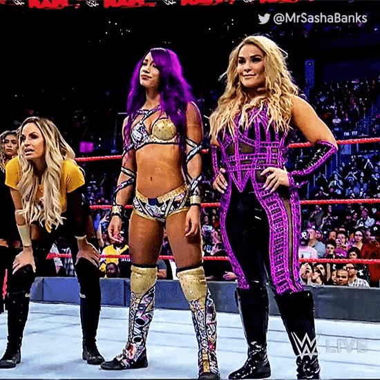 three female wrestlers are standing in a wrestling ring with purple hair