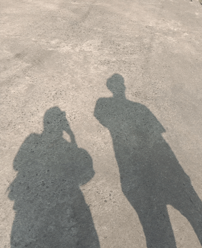 a shadow of a person taking a picture of another person on the ground