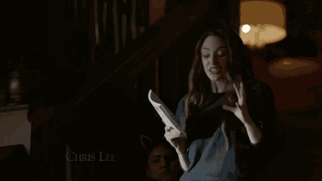 a woman is standing in a dark room with her hands on her hips