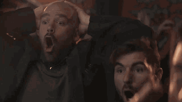 a couple of men are sitting in a dark room with their mouths open .