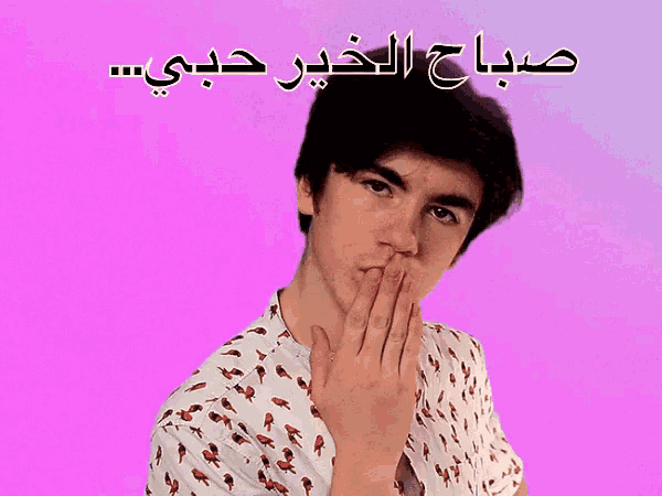 a man in a white shirt with a pink background and arabic writing