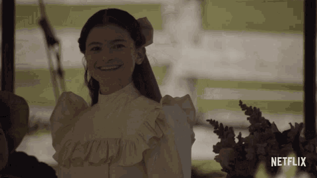 a girl in a white dress is smiling in front of a netflix sign