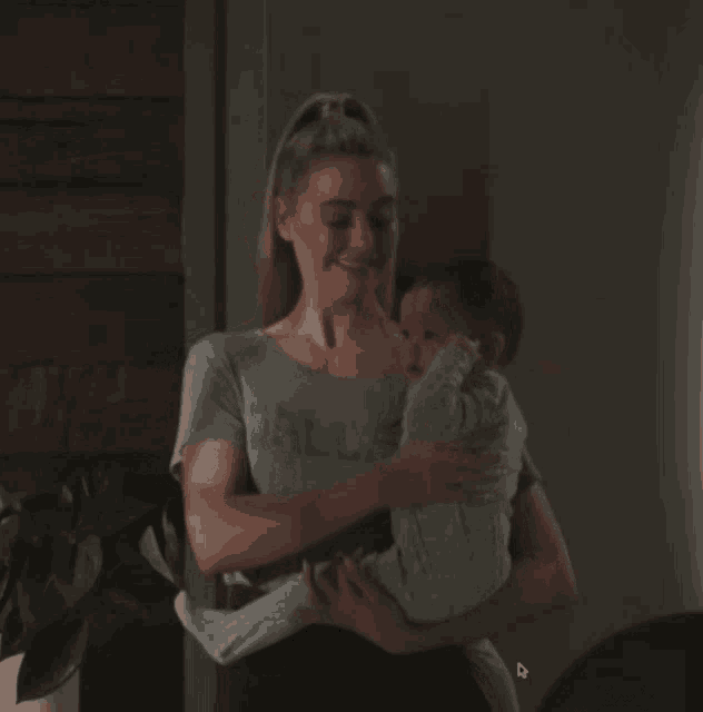 a woman holding a baby wearing a shirt that says dallas