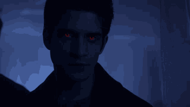 a close up of a man with red eyes in the dark