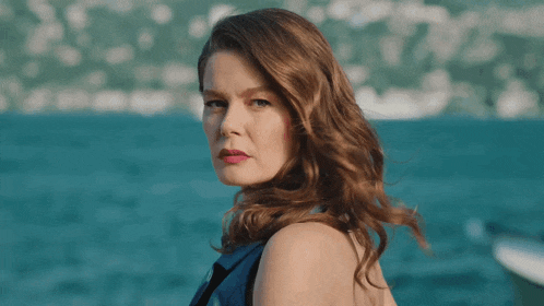 a woman in a blue dress is standing in front of a body of water
