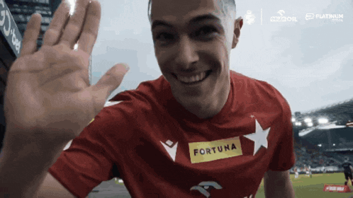 a man wearing a red shirt with the word fortuna on the front
