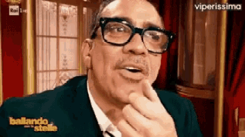 a man with glasses and a mustache is making a funny face while wearing a suit and tie .