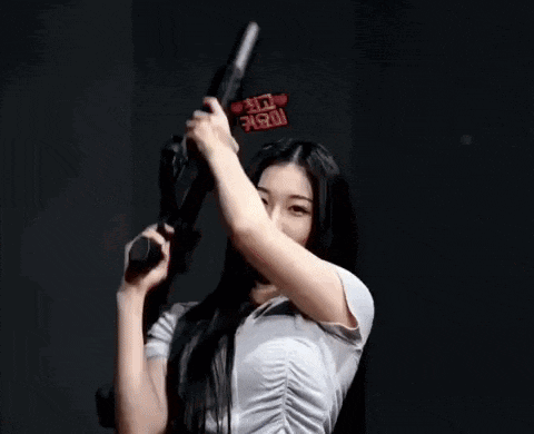 a woman is holding a gun over her head in front of her face .
