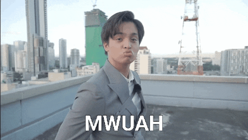 a man in a suit and tie is making a funny face and the word mwuah is on the bottom