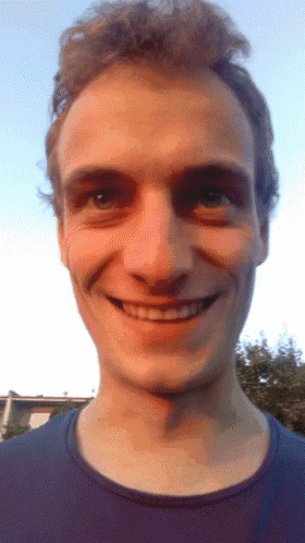 a close up of a man 's face with a blue shirt on