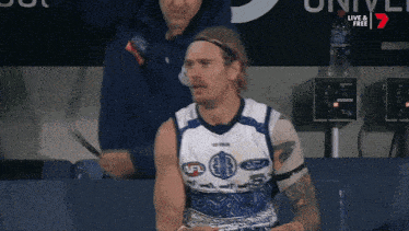 a man wearing an afl jersey sits in a locker room