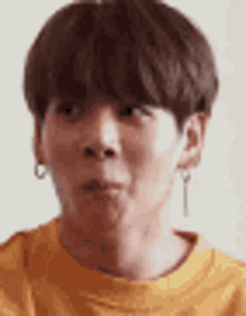 a close up of a person wearing a yellow sweater and earrings making a funny face .