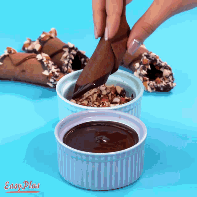 a person is dipping a chocolate cone into a small bowl of chocolate sauce