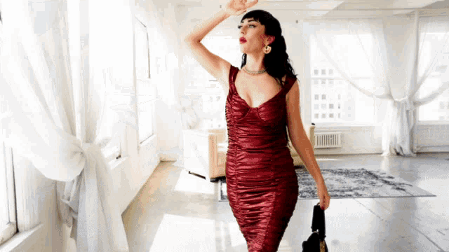 a woman in a red dress is holding a black purse