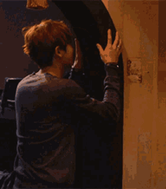a man is leaning against a wall with his hand on it