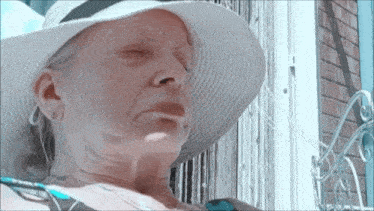 a woman wearing a white hat and earrings looks at the sun