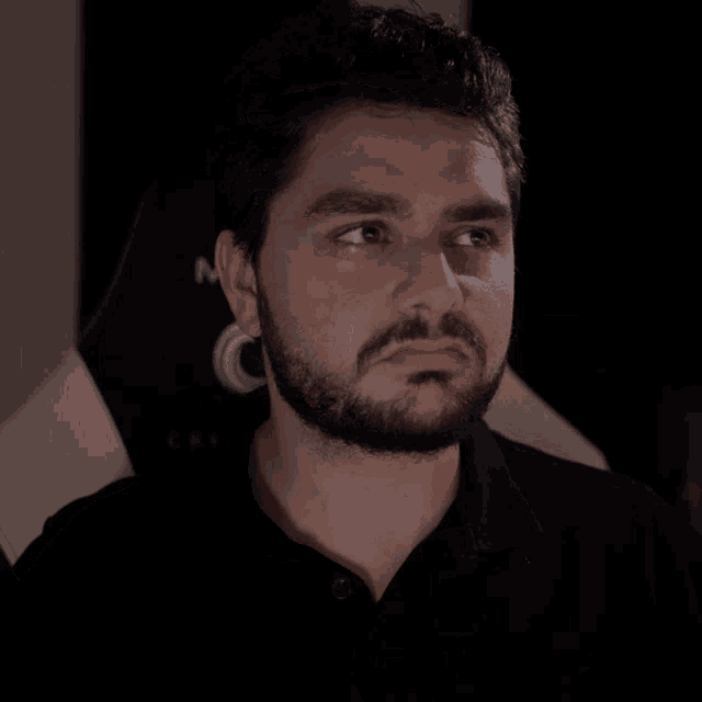 a man with a beard wearing a black polo shirt