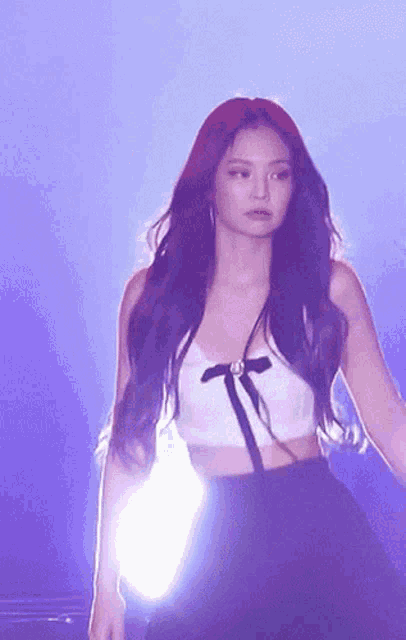 a woman with long purple hair is wearing a white crop top and a black skirt