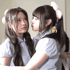 two girls are kissing each other and one has a smiley face in her hair .