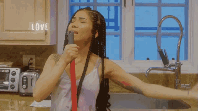 a woman brushing her teeth in a kitchen with a sign that says love
