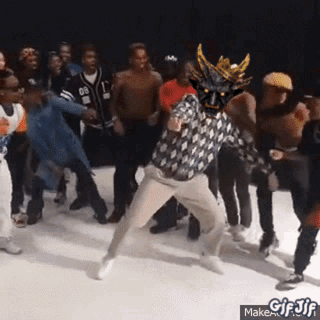 a group of people are dancing in a room with a man wearing a dragon mask .