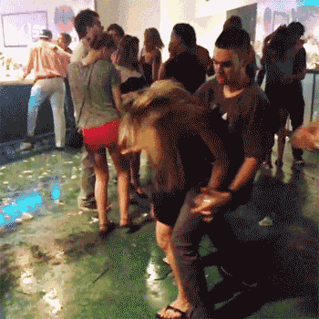 a group of people are dancing in a room with a lot of bottles on the floor