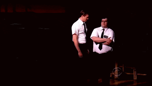 two men standing next to each other in a dark room and one has a name tag that says ' smith ' on it