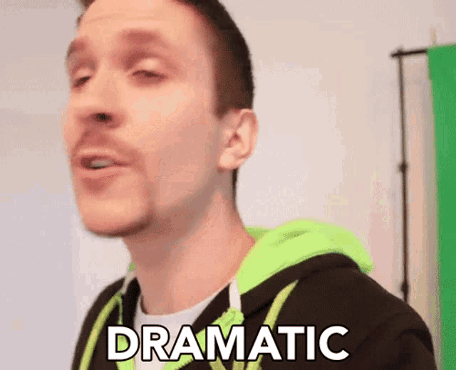 a man wearing a green hoodie says dramatic in front of a green screen