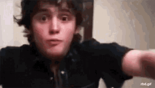 a close up of a young man taking a selfie with his hand outstretched .
