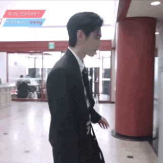 a man in a suit is walking in a hallway