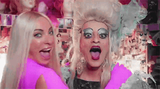 two drag queens are standing next to each other with their tongues out and making funny faces .