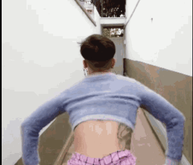 a man with a tattoo on his back is walking down a narrow hallway