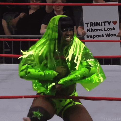 a wrestler in a neon green outfit holds a sign that says trinity khans lost impact won