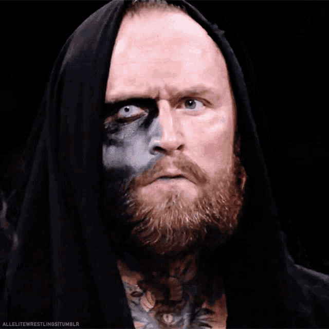 a man with a beard and black paint on his face is looking at the camera