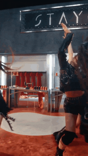 a woman is dancing in front of a sign that reads stay