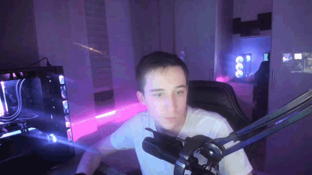 a young man is sitting in front of a microphone in a room with purple lights