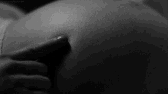 a black and white photo of a woman 's butt with a finger pointing at it
