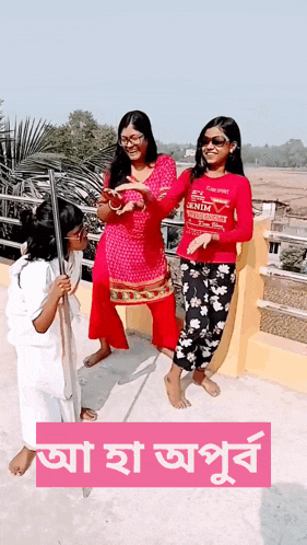 three girls standing on a balcony with one wearing a red shirt that says denim